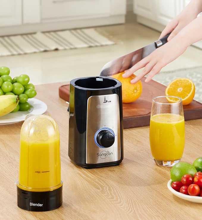Podstawa blendera Sangcon i kubek z napojem obok krojonej pomarańczy